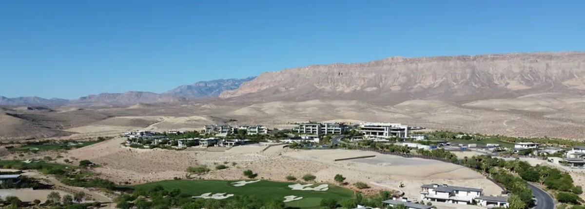 Aerial view of The Summit Club in Summerlin, with custom homes and open homesites above a golf fairway and the mountains to the west.